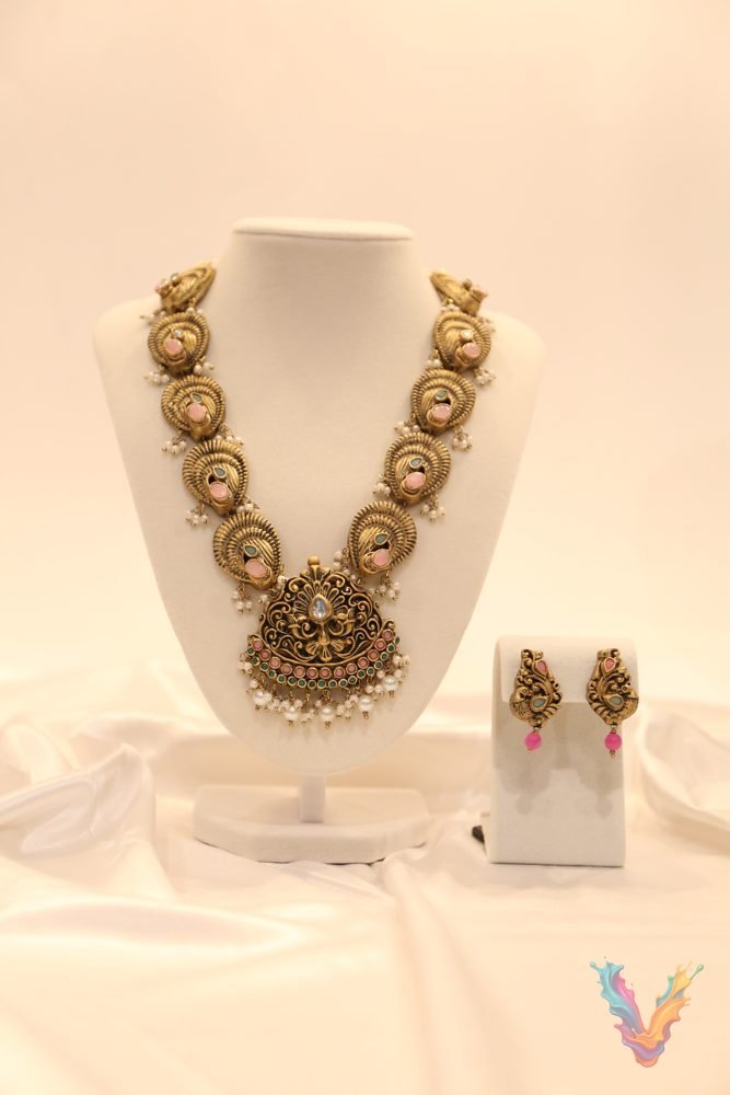 An ornate terracotta pendant necklace with matching earrings on a white jewellery bust