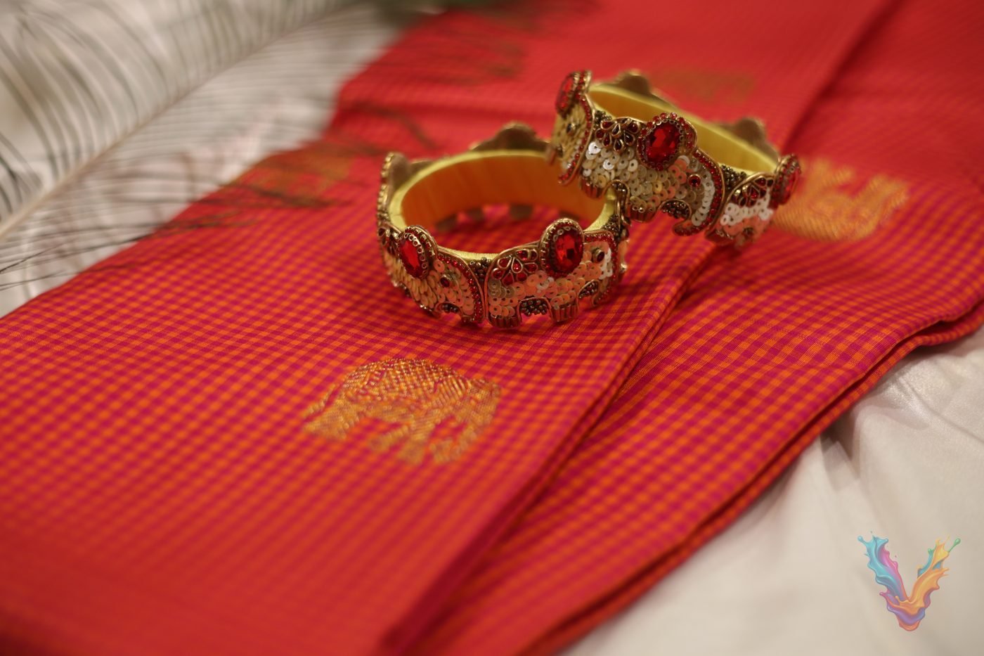 Golden stone studded bangle stack on a red silk saree