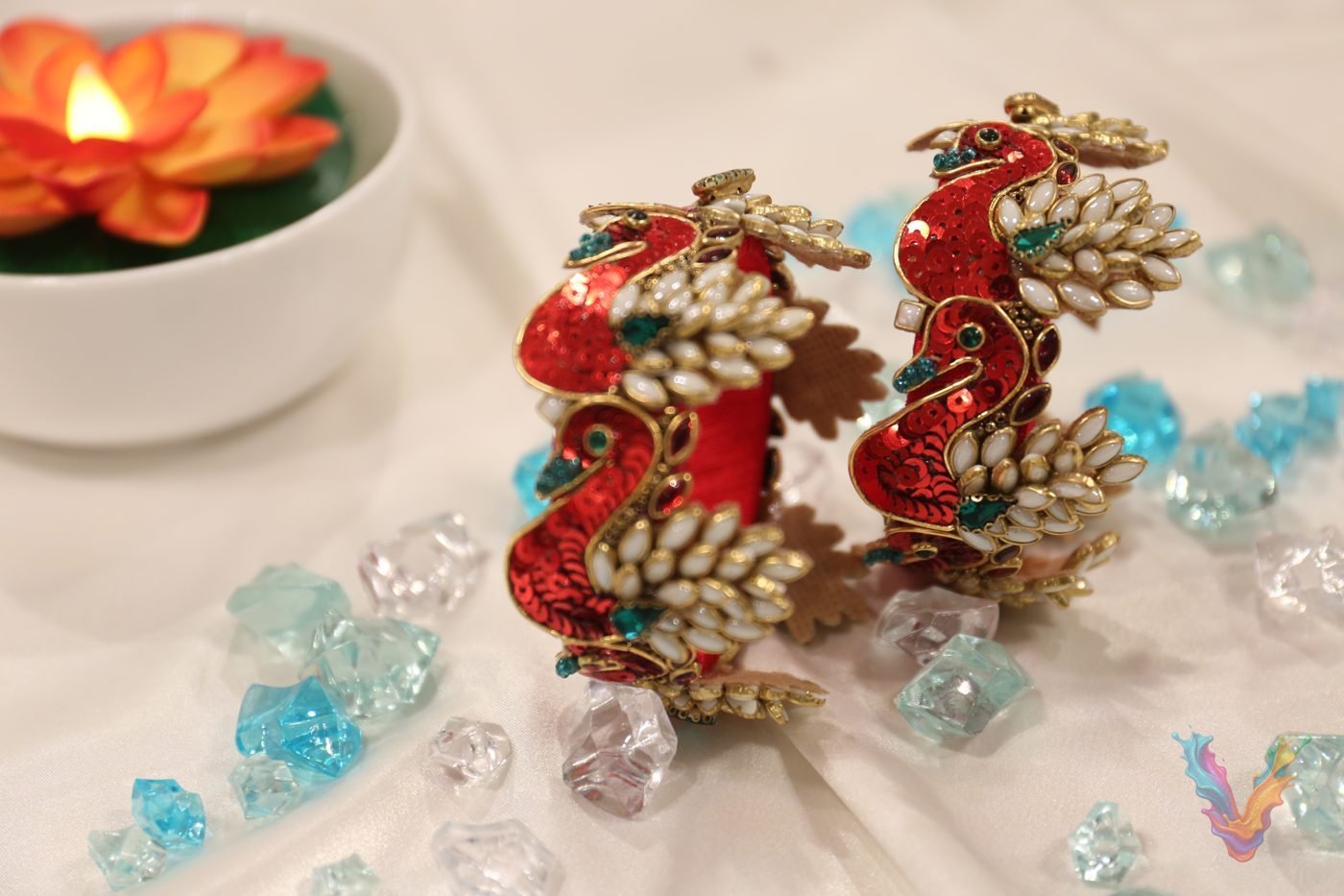 Pastel peacock bangle pair beside a lotus candle
