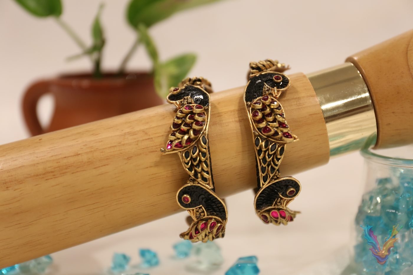 Black and gold parrot bangles with pink stones on a wooden stand