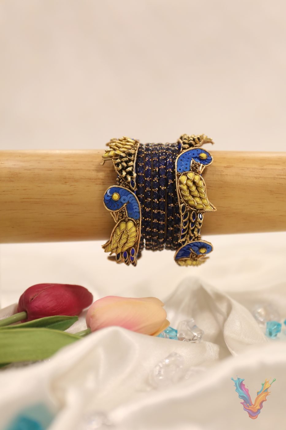 Green and gold peacock bangle set on a dark wooden stand