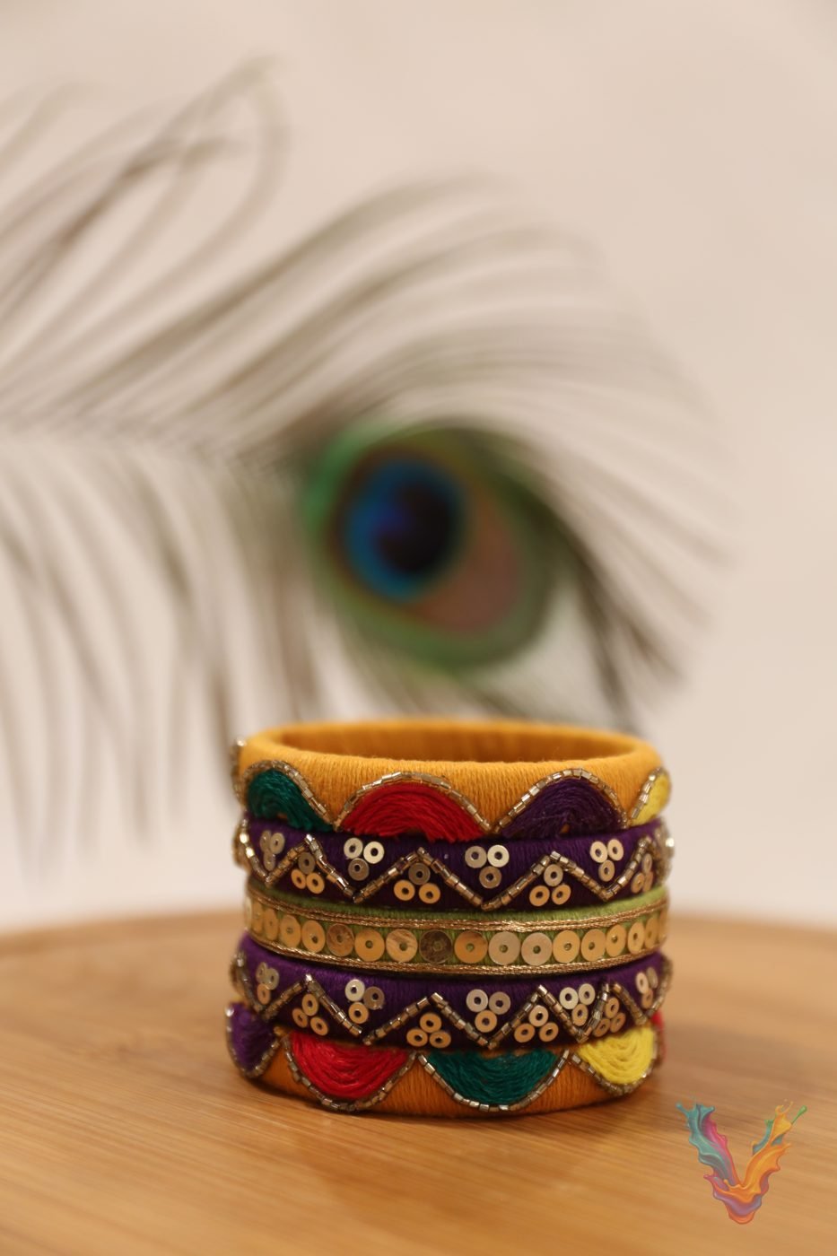 Multicolored silk thread bangle stack with a peacock feather