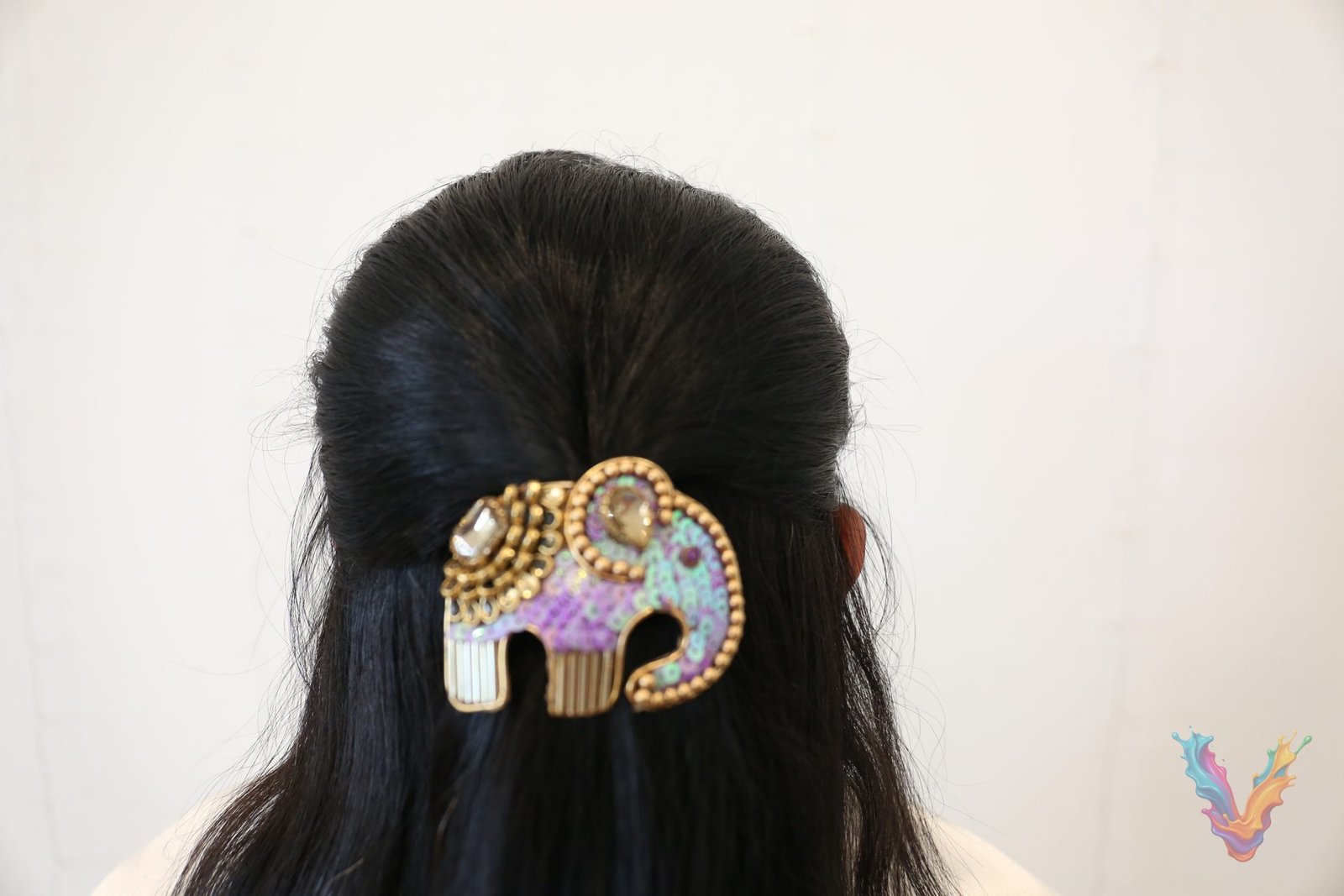 A hand embroidered elephant hair clip worn in long dark hair