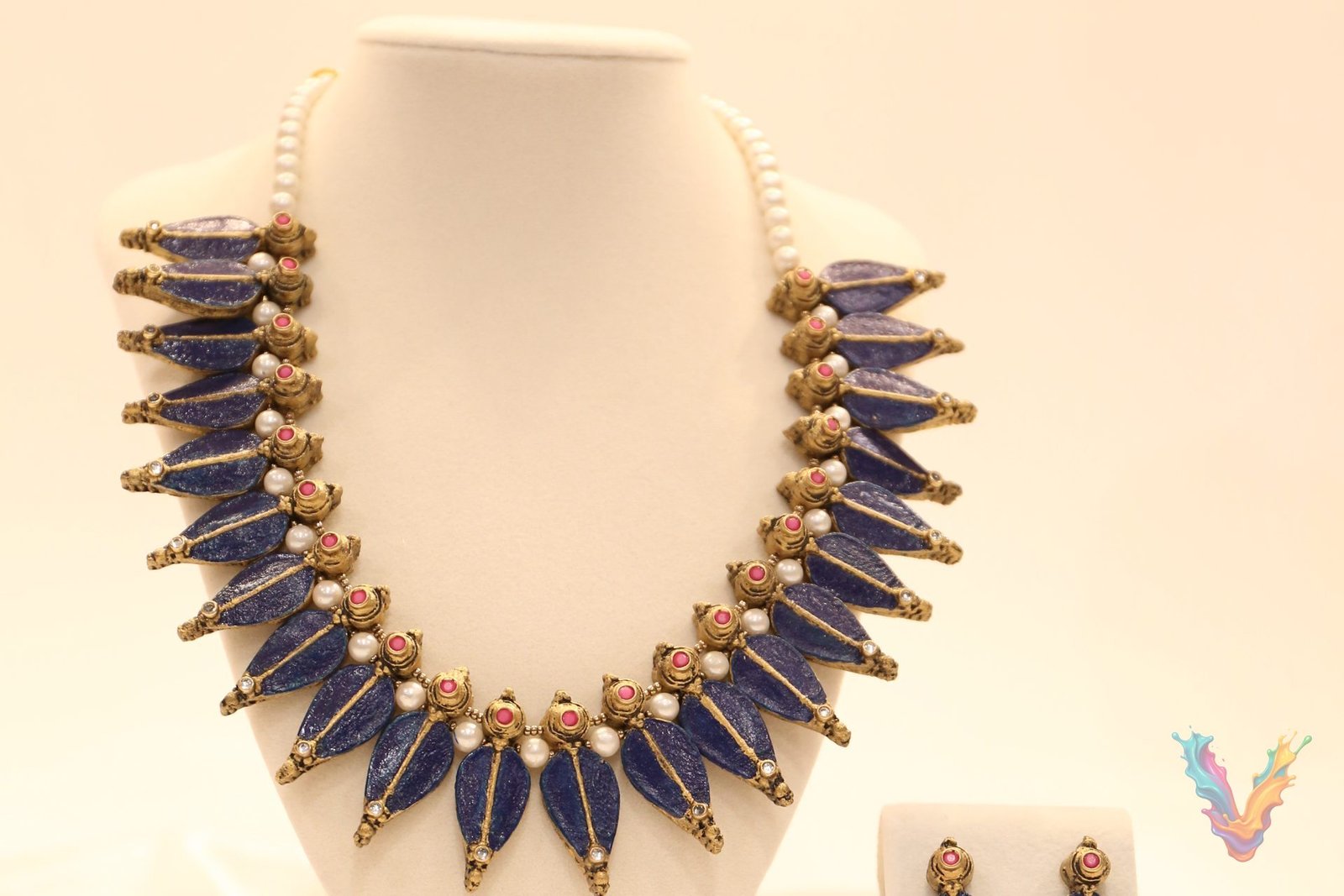 A blue and gold terracotta necklace with matching earrings displayed on a jewellery bust